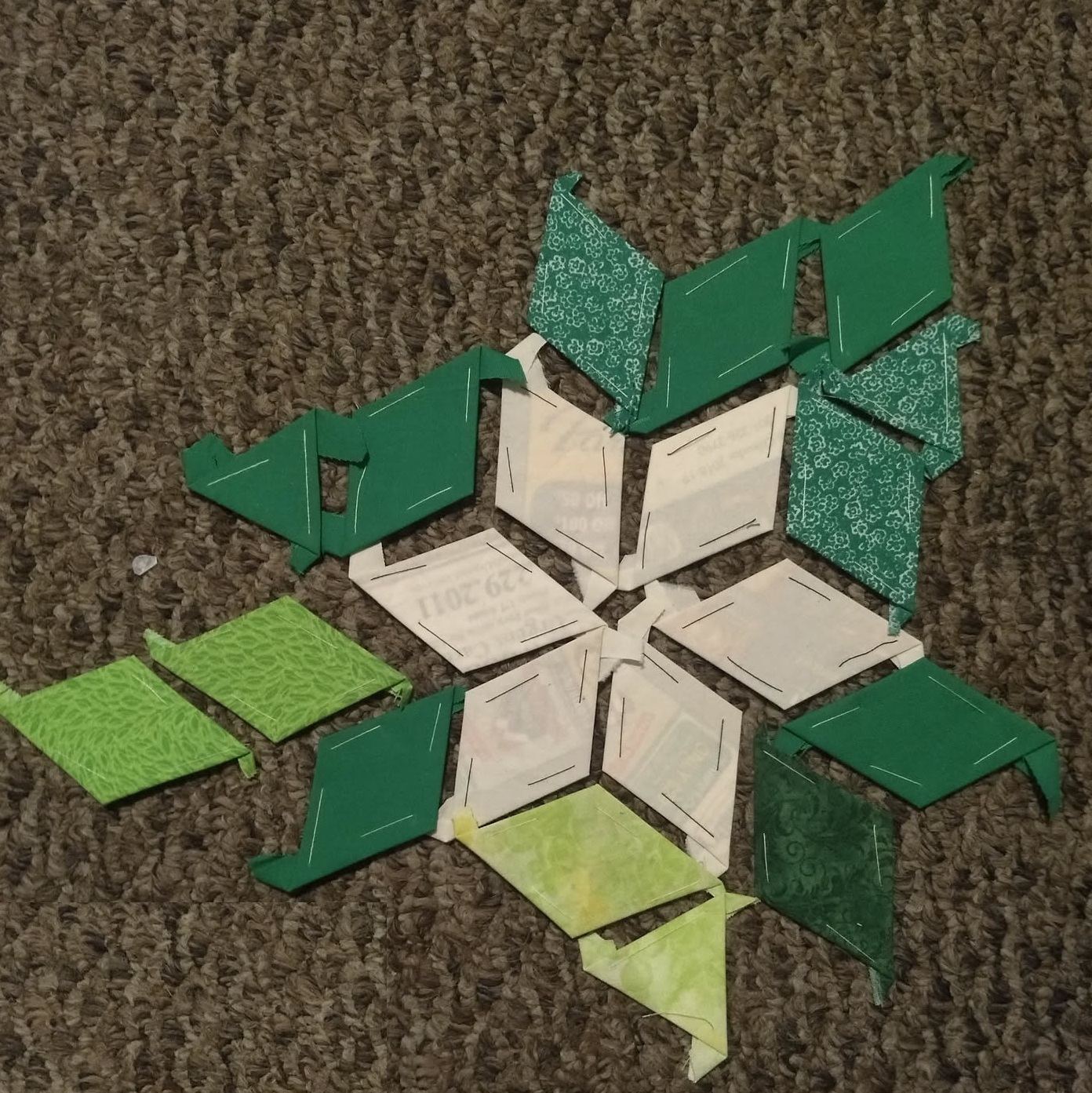A close-up of diamond fabric shapes basted around paper templates.